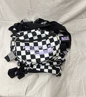 Stack of black and white checkerboard fanny packs with purple graphics