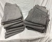 Stacks of gray denim jeans showing back pockets and stitching