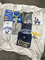 Nine of the women’s licensed sports T-shirts laid out on a cloth background