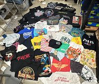 Overall view of 50 assorted men’s graphic T-shirts spread on floor