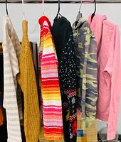 Six tops of varying colours and patterns hanging on rail, representing the assorted size S sweaters