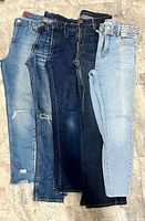 Front view of five pairs of size 31 women’s jeans in assorted washes laid flat