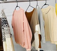 Five sweaters hung on rack showing design, color and overall condition