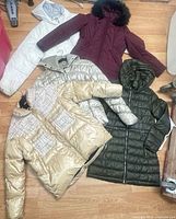 Five jackets arranged on floor showing colors and styles