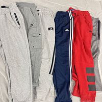 Six pairs of sweatpants laid side by side showing colours and logos