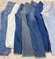 Seven pairs of assorted women’s jeans laid side-by-side to show color range and quantity