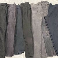 Seven pairs of women’s jeans laid flat showing backside and leg wash variations