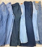 All seven pairs of jeans laid flat showing full length and waistband