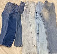 Seven pairs of women’s jeans laid flat showing color range and back pockets