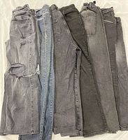 Seven pairs women’s jeans laid side by side showing colors, styles and wear