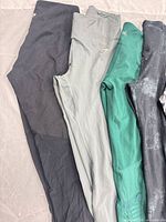 Four pairs of leggings showing colour variety (black, grey, green, dark wash)
