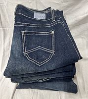 Stack of dark wash jeans showing back pocket stitching