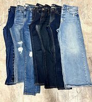 All seven pairs of women’s size 28 jeans laid flat showing front legs and waistbands