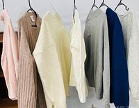 Front view of seven assorted women’s sweaters on hangers