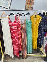 Seven dresses hanging on rack displaying full assortment