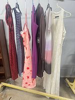 Seven dresses hanging on rack showing colors and styles