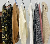 all seven women’s sweaters hanging on hangers showing styles and colors