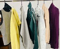 All seven sweaters hanging on rack displaying colors and styles