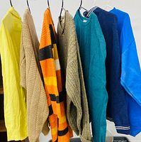 Seven assorted women’s XL sweaters hanging in a row, showing colors and styles