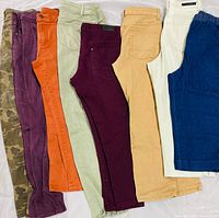 Eight pairs of assorted women’s jeans laid side by side showing colors and pattern