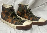 Three-quarter front view of both sneakers showing camouflage uppers, laces, toe caps and soles