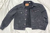 Full view front of black Levi's denim jacket laid flat