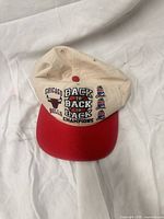 Front view showing Bulls logo and Back To Back To Back Champions embroidery on white crown with red brim