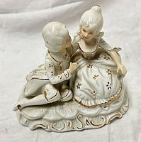 Front view of white porcelain couple figurine with gold trim