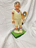front view of plaster tennis player figurine on green base