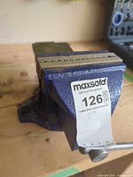 Front view of blue cast iron bench vise with 5" jaws and MaxSold lot tag