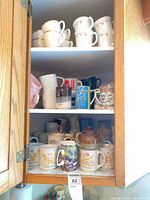 Cupboard shelves filled with mixed mugs and teapot