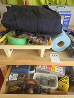 Lot overview showing coveralls, tape, towel roll, bags of tools, boxed stripper, organiser with fasteners, brace drill