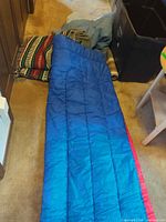 Blue sleeping bag laid out with blankets behind