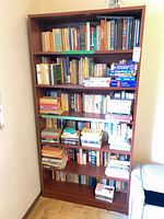 Full front view of brown veneer bookcase filled with books