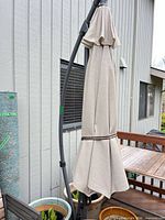 Folded beige/tan cantilever umbrella on dark gray curved pole