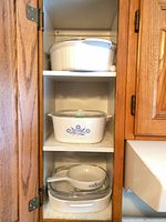 Cabinet shelves showing four CorningWare dishes and accompanying lids
