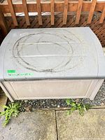 Top view of closed storage box showing gray lid with circular dirt marks and beige body