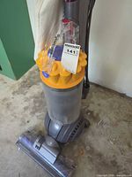 Full view of Dyson upright vacuum cleaner with clear canister and yellow cyclone top