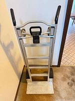 Front view of folding aluminum hand truck showing frame, handle grips, and wheels