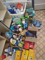 Overall view of baskets and boxes filled with cleaners, sponges, brushes, trash bags