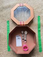 Open octagonal box showing two watches and pink coil