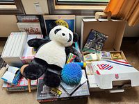 Group shot of plush panda, puzzles, books, card boxes, ball, and games