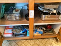 Cabinet view showing roasting pan, glass dishes, metal pans, muffin tin, mixing bowls and boxes
