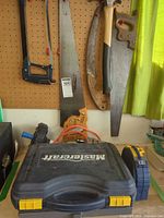 Overall lot showing saws on pegboard, Mastercraft case, tape measure