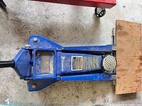 Top view of blue Michelin hydraulic floor jack on wooden tray