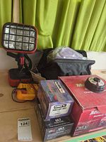 Group shot of boxed brake pads, battery charger, work light, multimeter, tool bag
