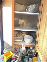Dinnerware and glassware stacked in cabinet, utensils below