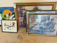 group shot of five framed artworks leaning against wall