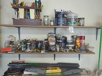 Shelves holding jars of fasteners, tool caddy, aerosol cans