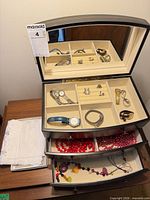 Jewelry box open showing watches, rings, bracelet and beaded necklaces